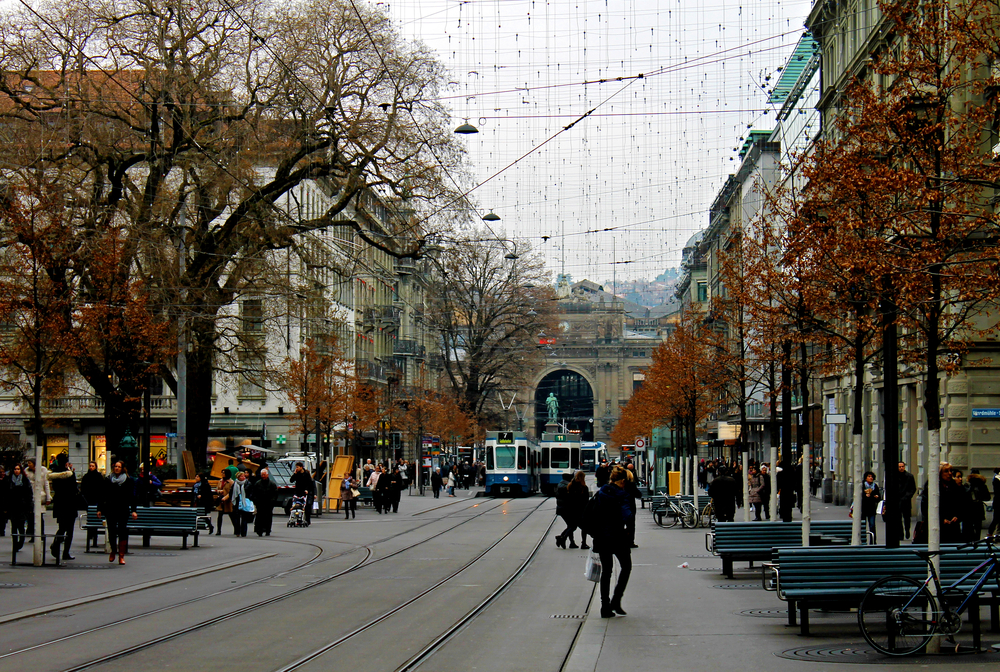 Bahnhofstrasse a Zurigo con i binari del tram, i pedoni e la stazione centrale in fondo alla via