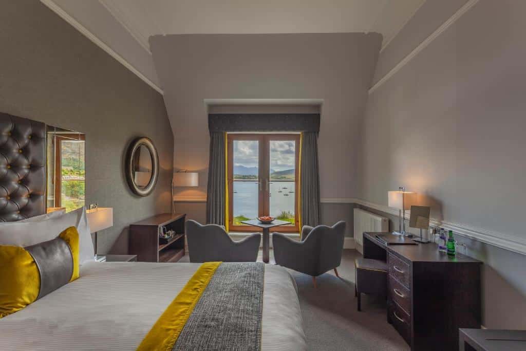 Una camera matrimoniale con sedie accanto alle finestre al Cuillin Hills Hotel di Portree