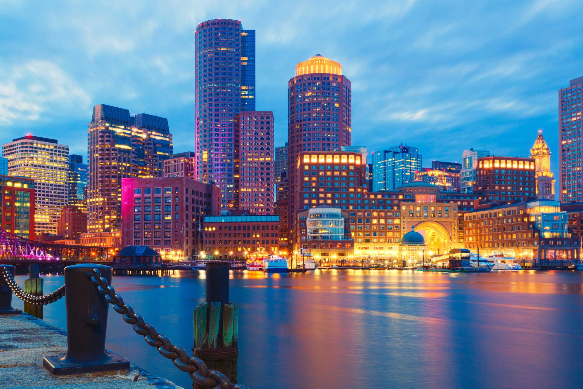 Edifici illuminati lungo il waterfront di Boston che si riflettono nell'acqua al crepuscolo
