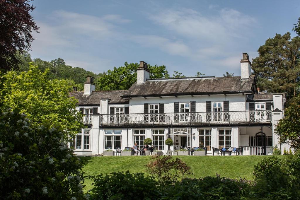 La facciata bianca e il balcone del Rothay Manor Hotel incorniciati dagli alberi del giardino