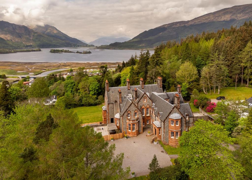 Glencoe House circondata dagli alberi con un lago e le montagne alle spalle