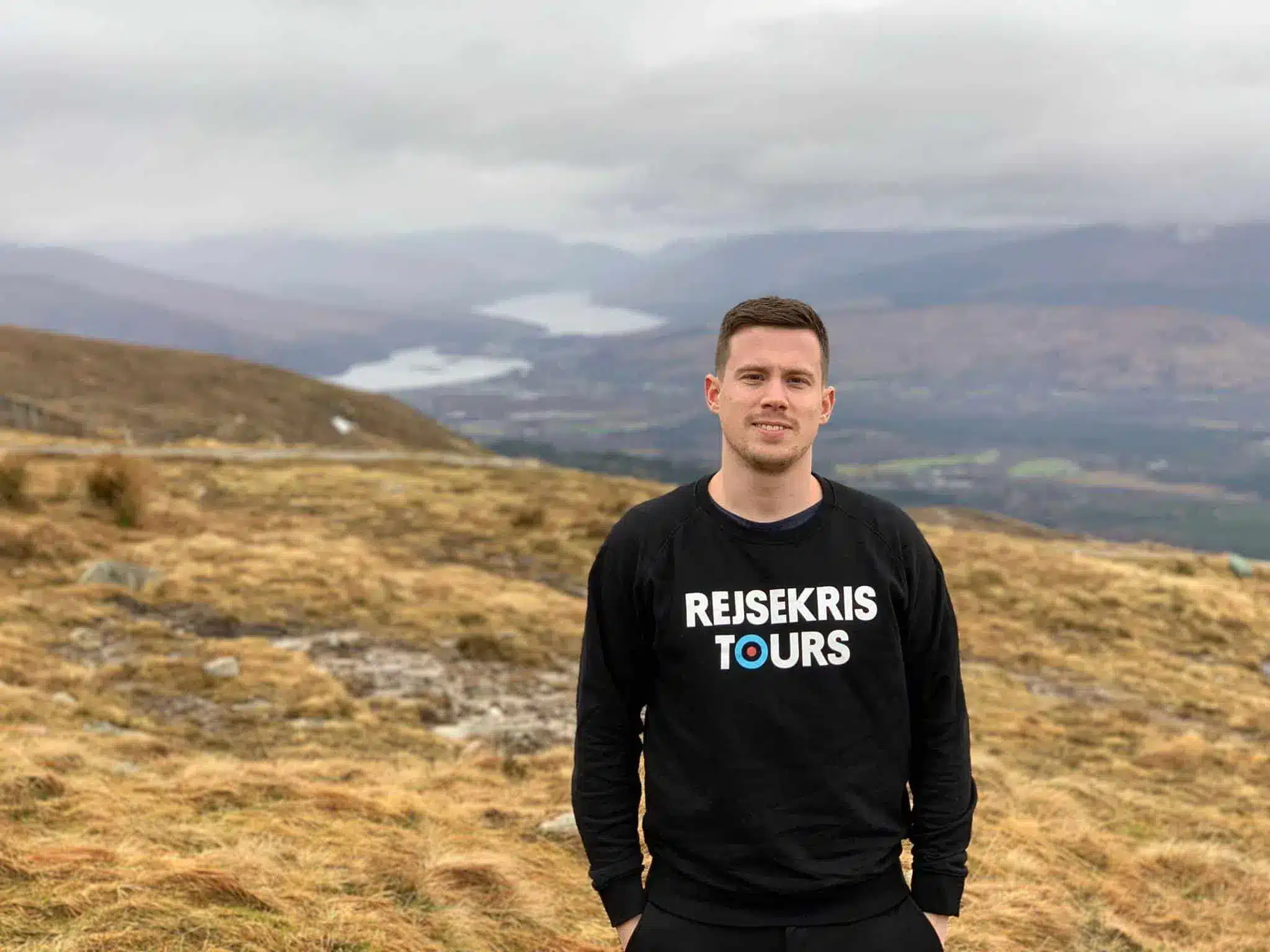 Kristoffer Fons di Destination Well Known su un pendio erboso con le montagne in lontananza vicino a Fort William