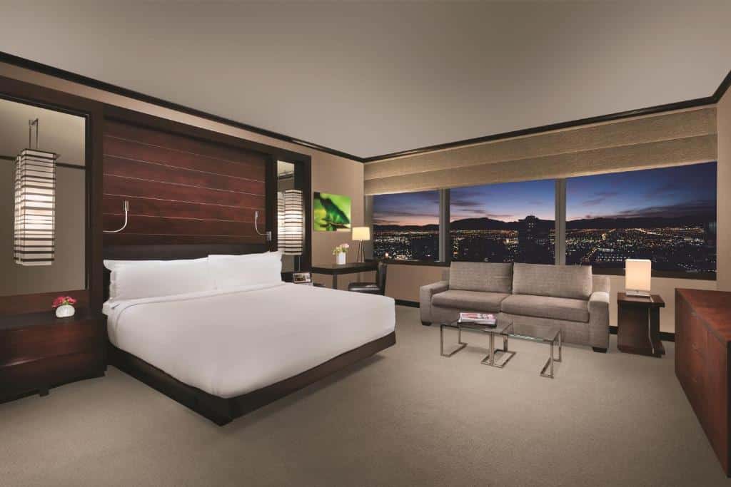 Letto e zona giorno accanto a grandi finestre in una suite del Vdara Hotel & Spa