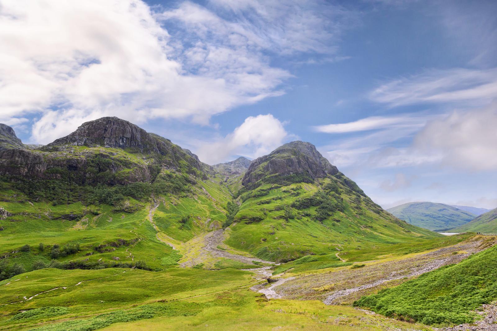 Pendii verdi e una strada nella valle sotto le Three Sisters di Glencoe